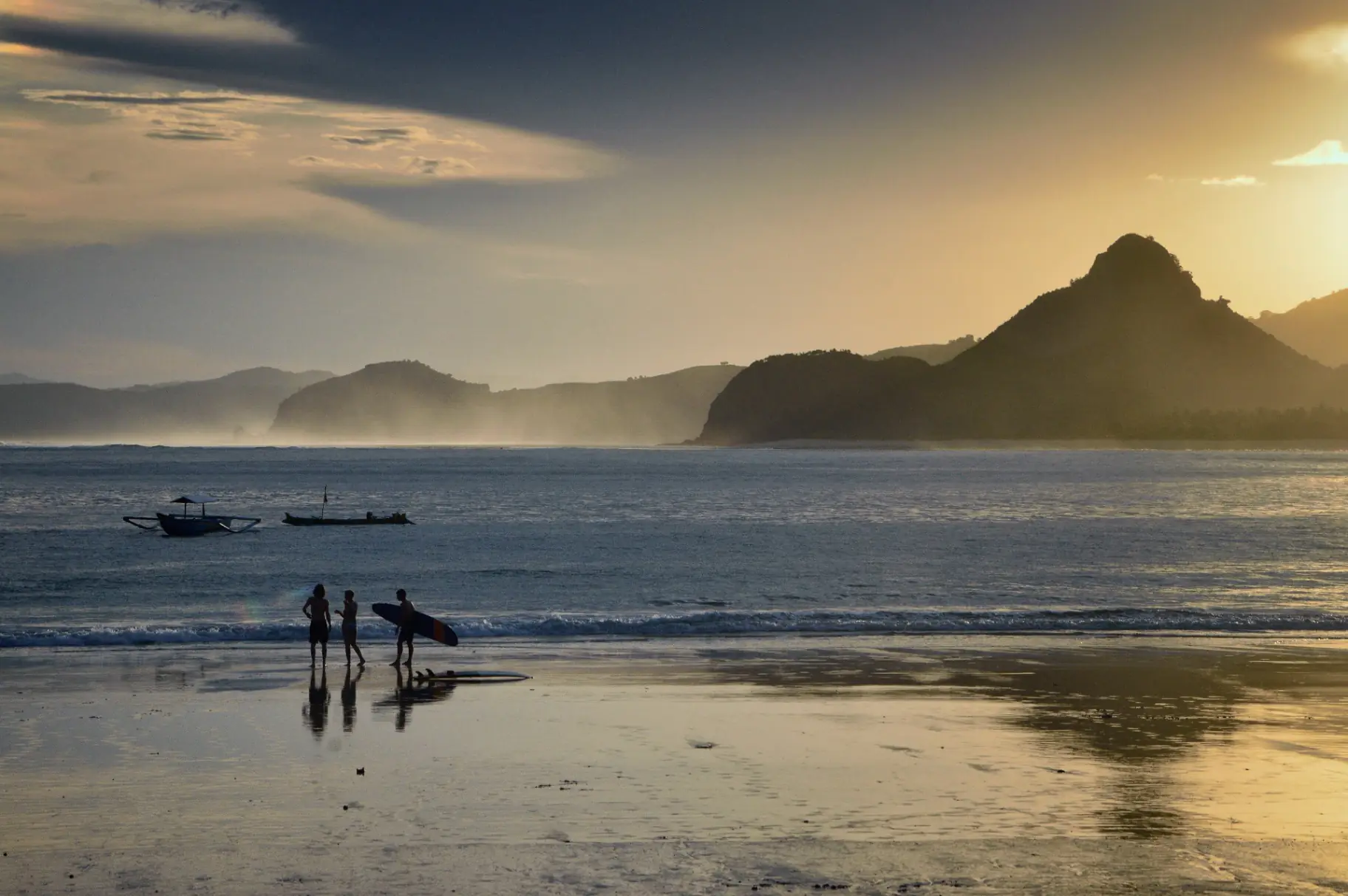 People walking along Selong Belanak beach at sunset
